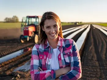 woman smiling in field with tractor